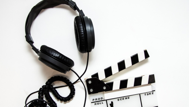 Austiņas ar vadu un filmu klape uz balta fona