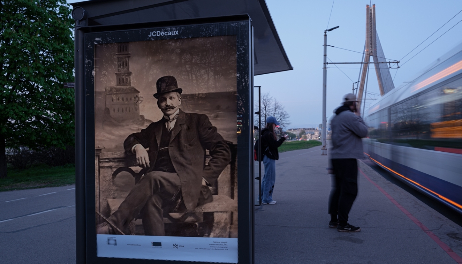 Rīgas Fotogrāfijas biennāles 2026 ārtelpas projekts “Iekštelpa–ārtelpa. Rīdzinieki salona fotogrāfijā. 19. gadsimta beigas – 1940” - foto sabiedriskā transporta pieturvietā