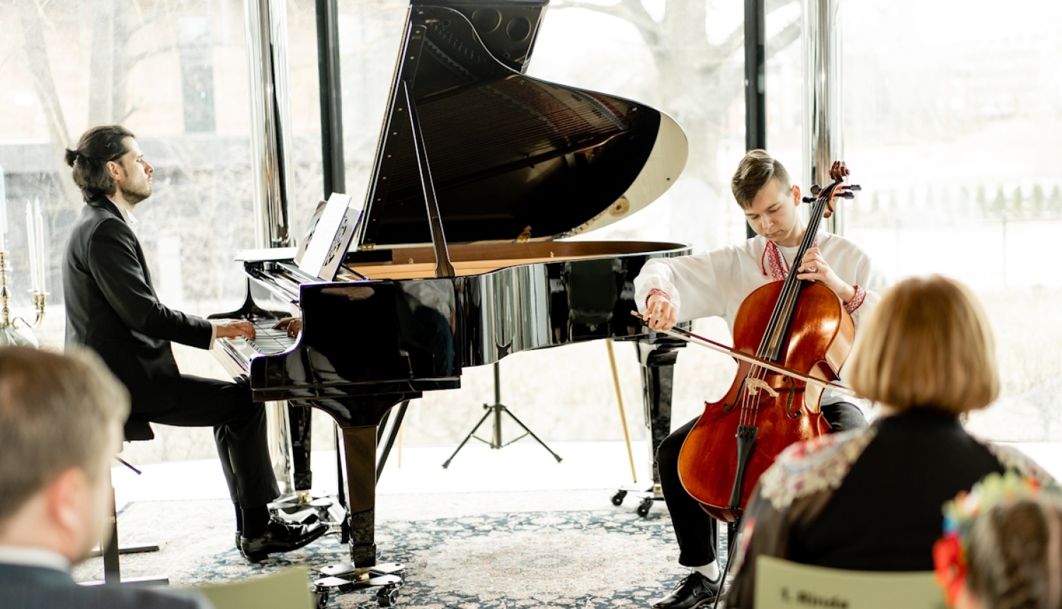 Pianists pie flīģeļa un jauns čellists spēlē nometnes koncertā