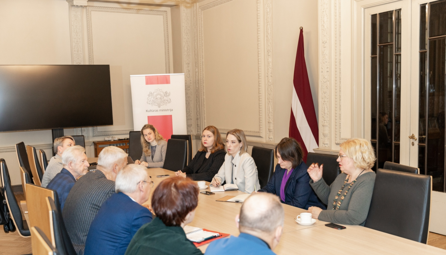 Cilvēki pie sanāksmju galda