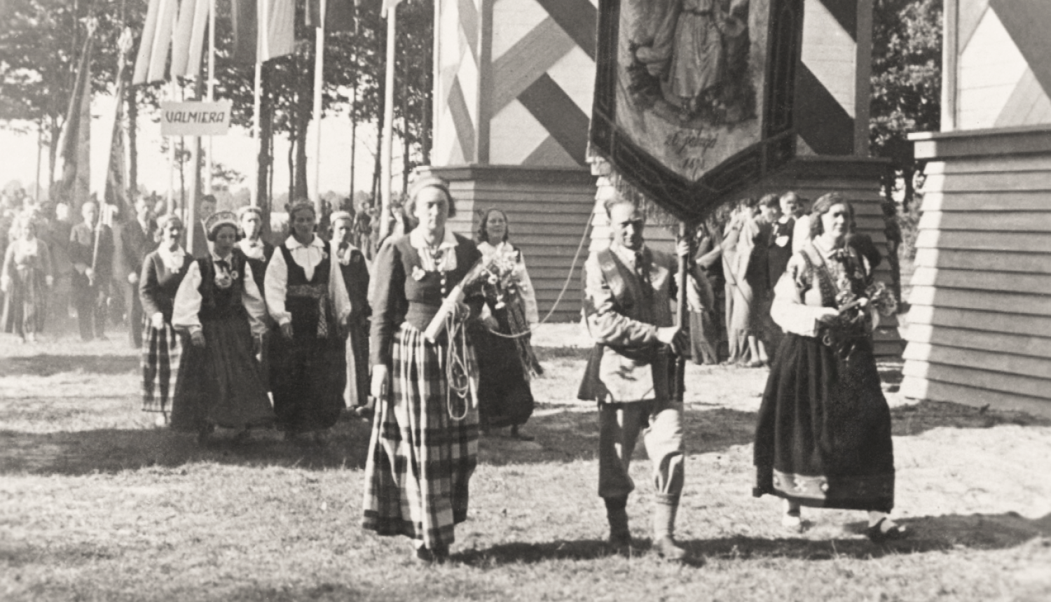 Melnbalta sena fotogrāfija, kurā redzami Dziesmu un deju svētku dalībnieki