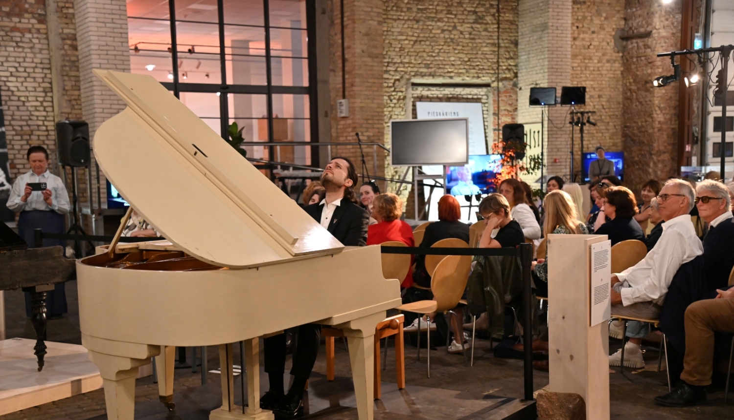 Pianists Aleksandrs Osokins pie flīģeļa klausītāju pilnā zālē
