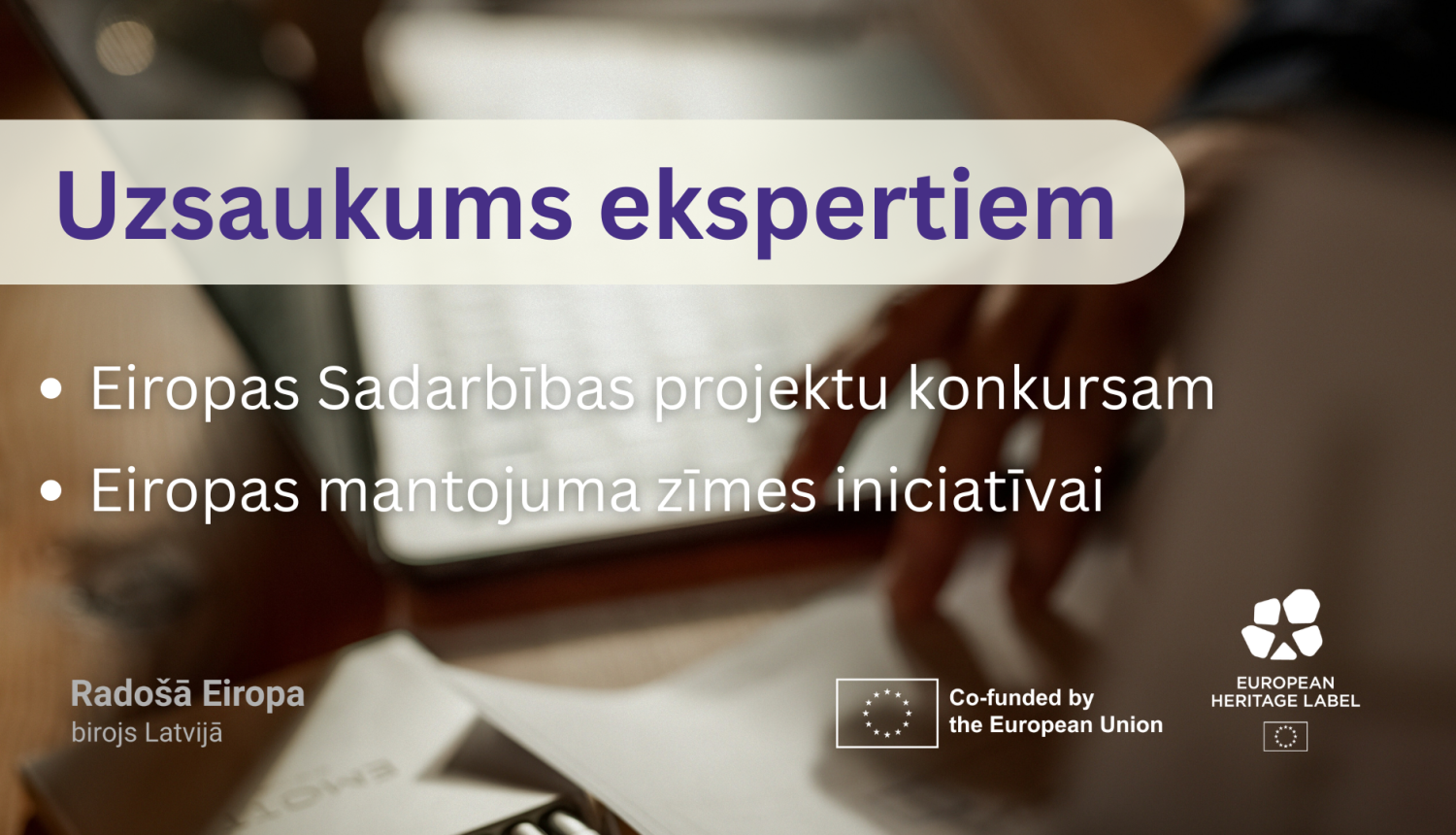 Attēla fonā ir redzams rakstāmgalds ar datoru un pierakstiem uz tā, labajā pusē ir redzama roka, kas darbojas ar papītiem. Attēlam virsū ir redzams teksts "Uzsaukums ekspertiem Eiropas Sadarbības projektu konkursam un Eiropas mantojuma zīmes iniciatīvai", zem teksta ir izvietoti logotipi.