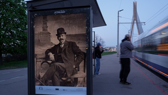 Rīgas Fotogrāfijas biennāles 2026 ārtelpas projekts “Iekštelpa–ārtelpa. Rīdzinieki salona fotogrāfijā. 19. gadsimta beigas – 1940” - foto sabiedriskā transporta pieturvietā