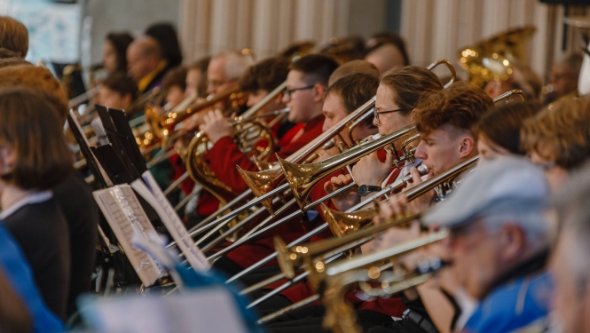 Pūtēju orķestris koncertā, fokusā trompetisti un trombonisti