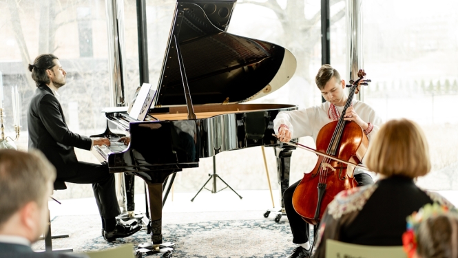 Pianists pie flīģeļa un jauns čellists spēlē nometnes koncertā
