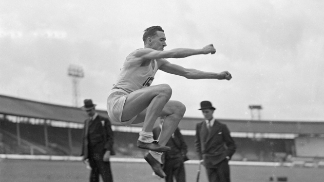Izrādes “Trešās impērijas bailes un posts” publicitātes foto - melnbalta fotogrāfija, kurā redzams stadions, skatītāji un sportists tāllekšanas disciplīnā