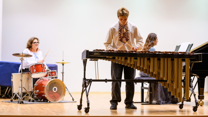 Divi mūziķi uz skatuves; viens pie bungām, otrs pie marimbas