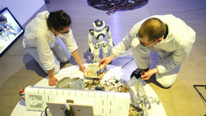 Robots NaoMi ar jaunajiem māksliniekiem Laimu Graždanoviču un Jurģi Peteru rezidencē “Kontakt/Ligzda”, RIXC galerijā. Foto: Juris Rozenbergs.
