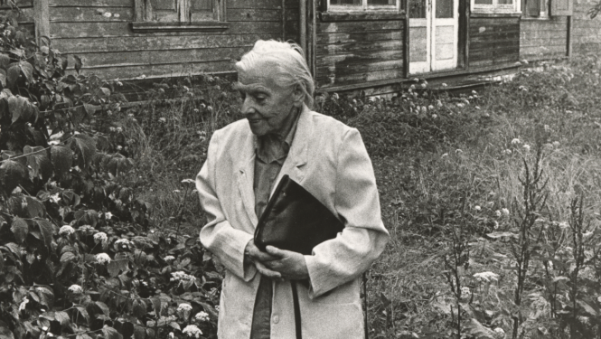 Melnbalts foto ar veca gadagājuma sievieti pie vecas lauku mājas