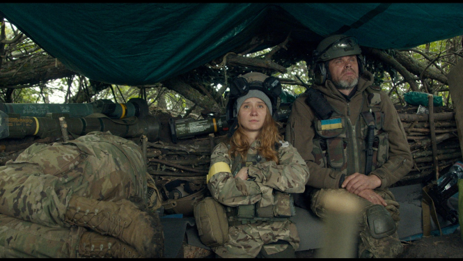 Kadrs no ukraiņu dokumentālistes Alisas Kovalenko jaunākās filma “Manu mīļo Teo” (My Dear Theo), kadrā telsts ar armijas ekipējumu un diviem armijas formastērpā tērptiem cilvēkiem