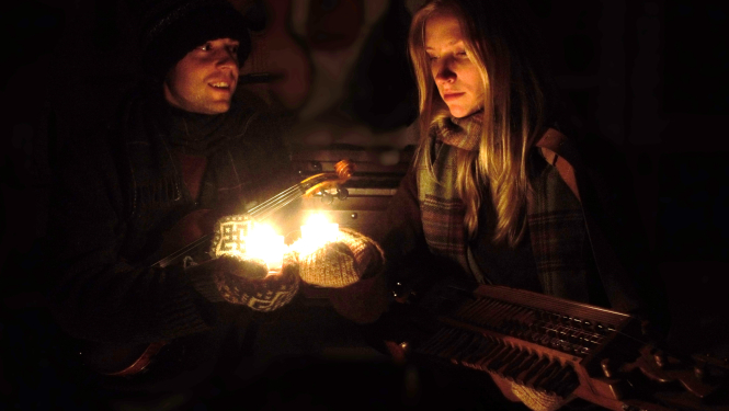 Cilvēki ziemas naktī pie aizdegtas laternas