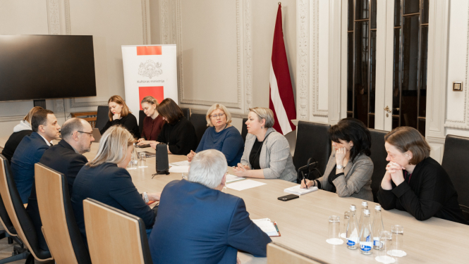 Vienpadsmit cilvēki pie sanāksmju galda