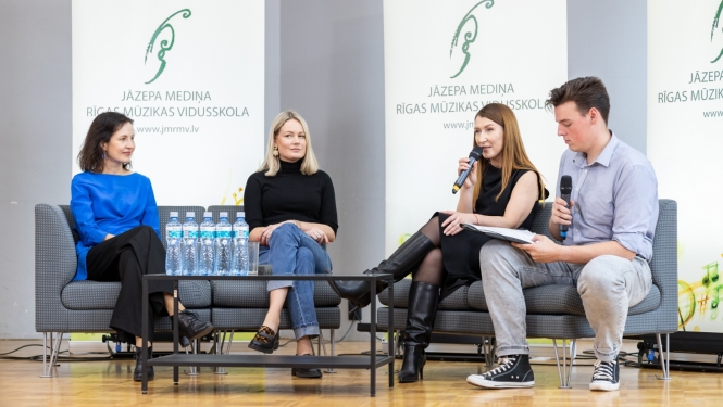 Četri cilvēki diskutē uz skatuves