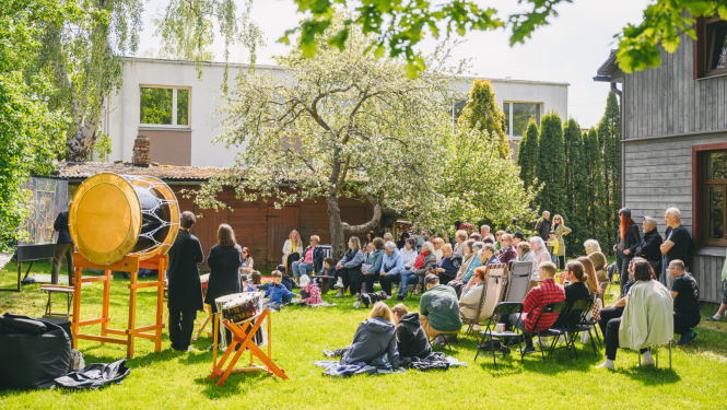 Kopienu programmas pasākums kādā pagalmā starp mājām ar pasākuma apmeklētājiem