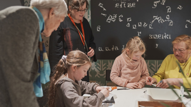 foto redzama Ģimenes dienas norise muzejā, kadrā bērni un pieaugušie radošajā darbnīcā