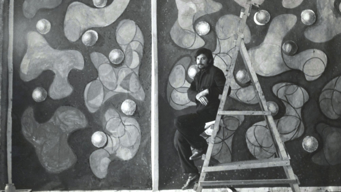 Jānis Krievs pie vitrāžas sienas projekta Rīgas sporta pilī. 1970. Publicitātes foto