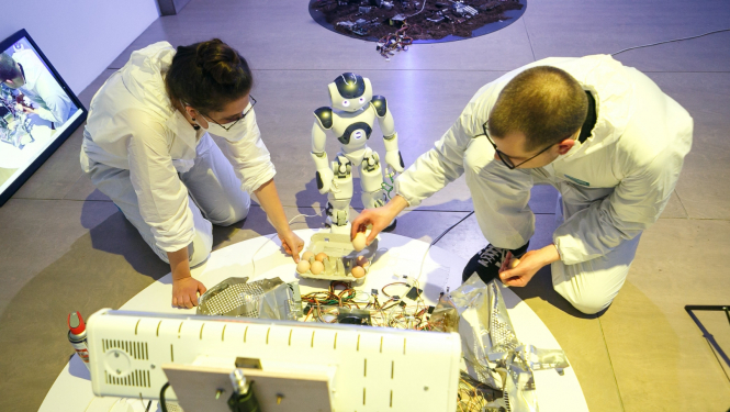 Robots NaoMi ar jaunajiem māksliniekiem Laimu Graždanoviču un Jurģi Peteru rezidencē “Kontakt/Ligzda”, RIXC galerijā. Foto: Juris Rozenbergs.