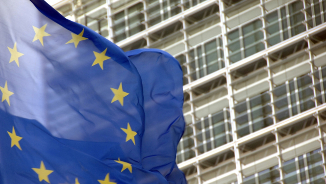 Eiropas Savienības karogs plīvo uz daudzstāvu ēkas fona