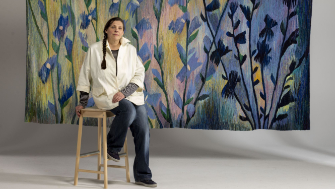 Tekstilmākslinieces Ivetas Vecenānes portrets ar gobelēnu “Cigoriņi” (2019). 2025. Foto: Didzis Grodzs