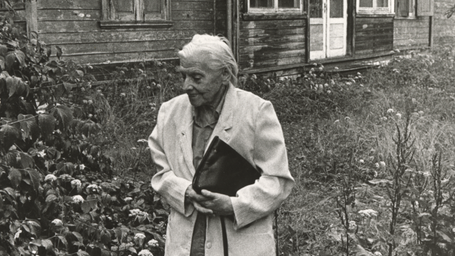 Melnbalts foto ar veca gadagājuma sievieti pie vecas lauku mājas