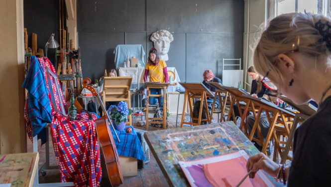 Vairāki audzēkņi telpā glezno