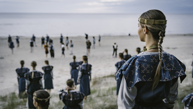 Cilvēki tautastērpos jūras krastā