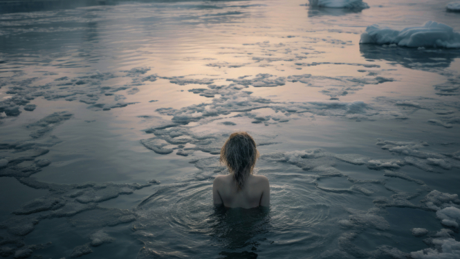 Izrādes publicitātes attēls, sievietes ķermeņa siluets no mugurpuses, kas līdz pleciem ledainā ūdeni
