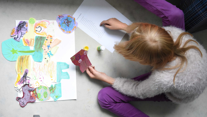 Bērns radošajā darbnīcā ar rakstampiederumiem un papīra izgriezumiem