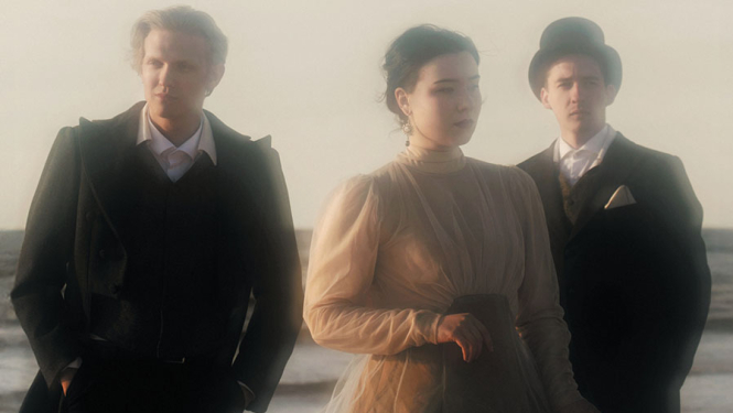 Trīs mūziķi uz jūras ainavas fona