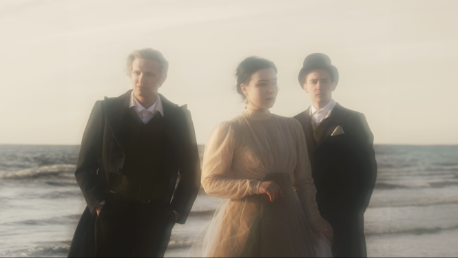 Trīs jaunie mākslinieki – soprāns Etīna Emīlija Saulīte, pianists Daniils Mickevičs un aktieris Artis Jančevskis uz jūras fona