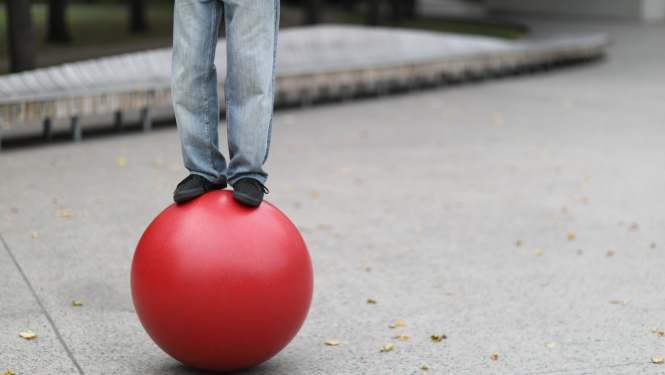 Uz sarkanas bumbas stāv cirka akrobāts