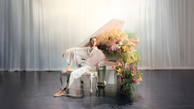 Iestudējuma afiša. Aktieris Maksims Busels pie baltam klavierēm