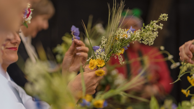 Cilvēki pin Jāņu vainagus
