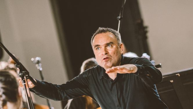 diriģents Jērgs Vidmanis orķestra priekšā diriģē koncertā