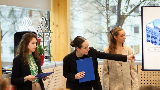 Trīs jaunietes prezentē projektu auditorijas priekšā