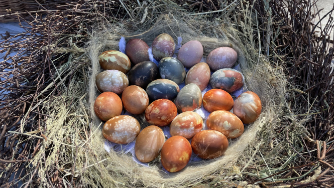 Krāsotas Lieldienu olas no zariem vītā grozā