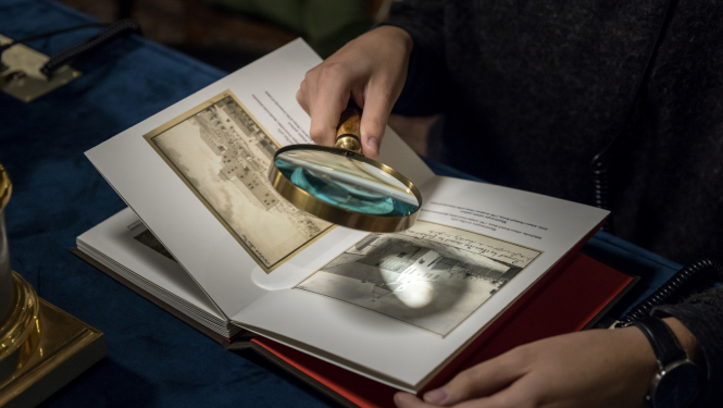 Persona ar palielināmo stiklu pēta saturu grāmatā