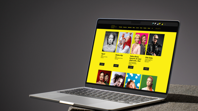 Dators uz galda. Ekrānā redzams Latvijas Nacionālā teātra repertuāra saraksta skats ar izrāžu reklāmas fotogrāfiju galeriju