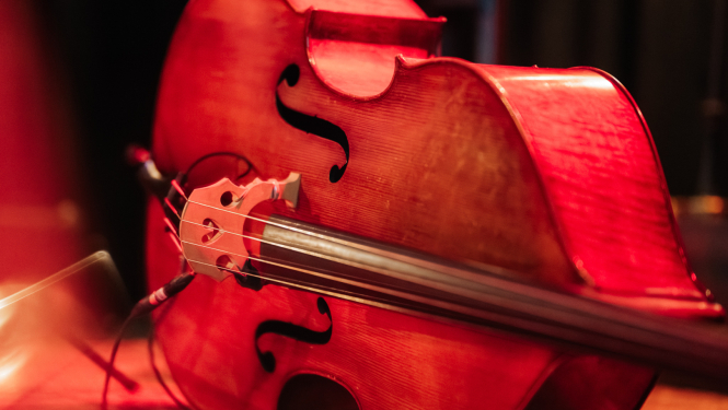 Uz skatuves guļošs kontrabass oranžās lampu gaismās