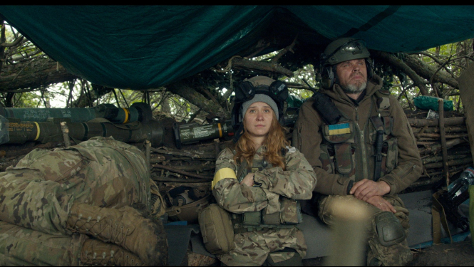 Kadrs no ukraiņu dokumentālistes Alisas Kovalenko jaunākās filma “Manu mīļo Teo” (My Dear Theo), kadrā telsts ar armijas ekipējumu un diviem armijas formastērpā tērptiem cilvēkiem