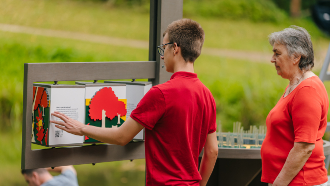 Cilvēki pie interaktīvas brīvdabas ekspozīcijas Turaidas muzejrzervātā