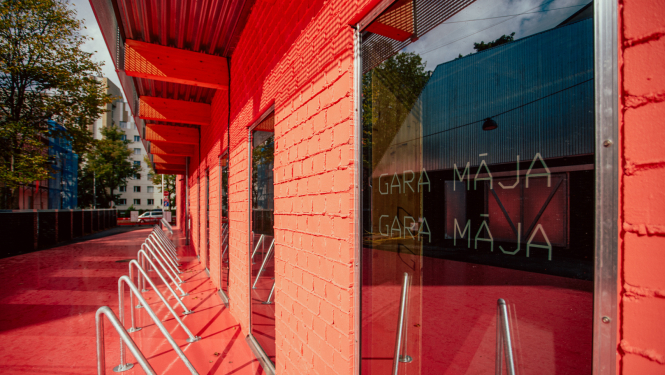 Kultūras un radošo industriju atbalsta centra “TabFab” "GARA MĀJA" sāna foto ar logiem, oranžu ietvi un velosipēdu novietni