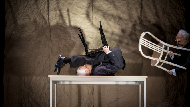 Divi aktieri uz skatuves izpilda vingrojumus ar krēsliem