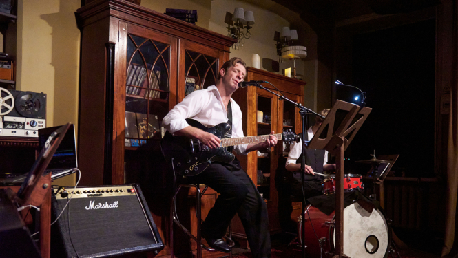 Aktieris uz skatuves spēlē ģitāru un dzied