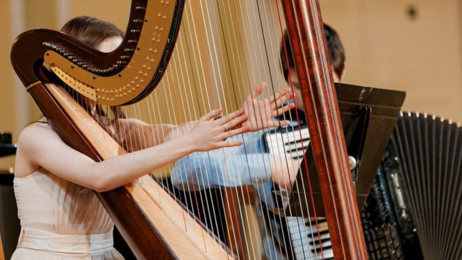 Meitene spēlē arfu uz skatuves