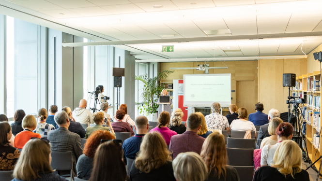 Mācību apmeklētāji klausās priekšlasījumu bibliotēkas telpā