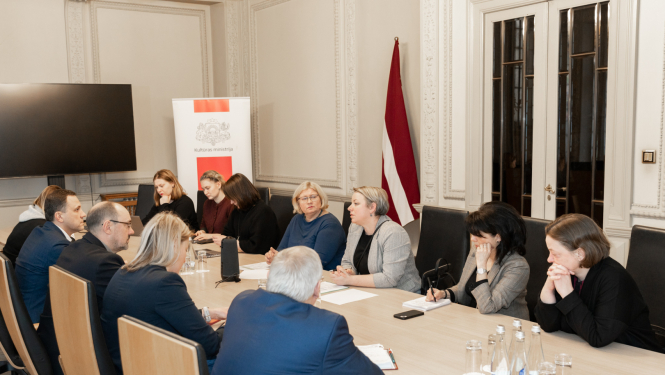 Vienpadsmit cilvēki pie sanāksmju galda