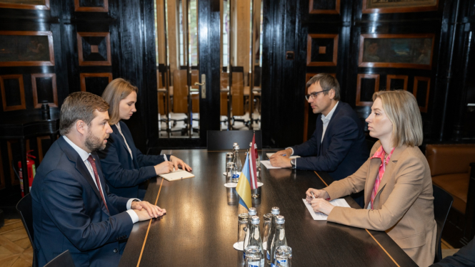 Četri cilvēki sanāksmju telpā pie galda