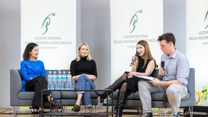 Četri cilvēki diskutē uz skatuves